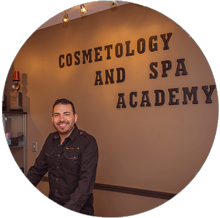 Man posing in front of Cosmetology & Spa Academy sign